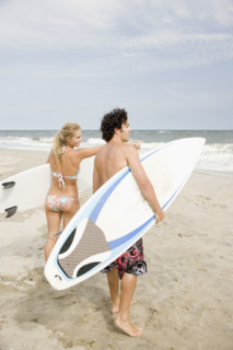 Couple holding surfboards at beach. Date : 2007