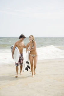 Couple carrying surfboards at beach. Date : 2007