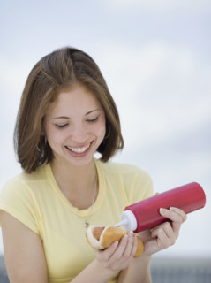 Woman putting ketchup on hotdog. Date : 2007