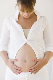 Pregnant woman smiling at belly. Date : 2007