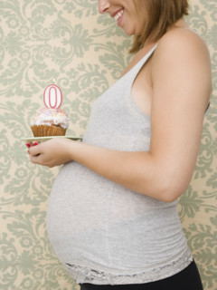 Pregnant woman holding cupcake with zero candle. Date : 2007
