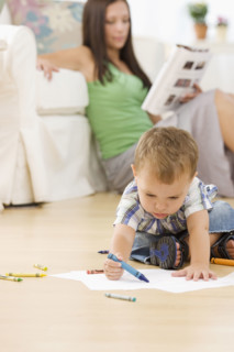Mother reading while baby colors. Date : 2007