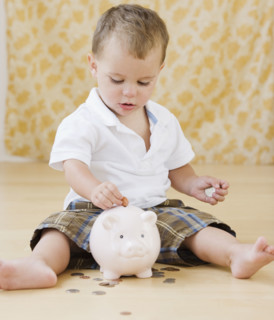 Baby putting coins in piggy bank. Date : 2007