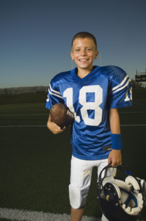 Young football player holding ball and helmet. Date : 2007