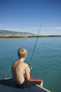 Boy fishing off dock in lake, Utah, United States. Date : 2007