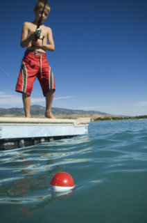 Boy fishing off dock in lake, Utah, United States. Date : 2007