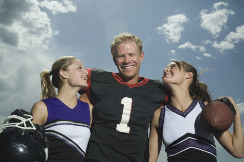 Football player hugging cheerleaders. Date : 2007