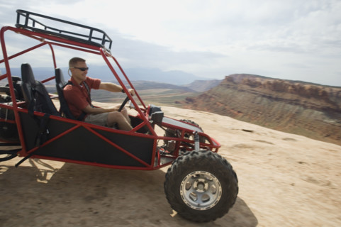 Man in off-road vehicle on rock formation. Date : 2007