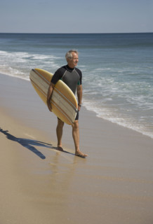 Man carrying surfboard at beach.