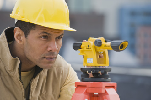 African male surveyor looking through measuring device.