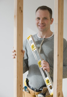 Male construction worker holding level tool.