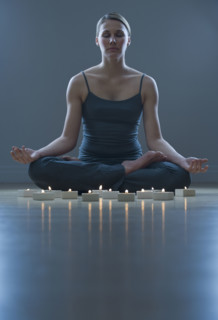 Woman meditating next to candles.