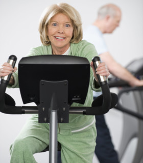 Senior woman riding on exercise machine.