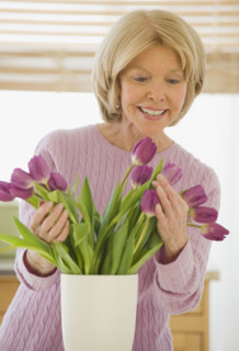 Senior woman arranging flowers.