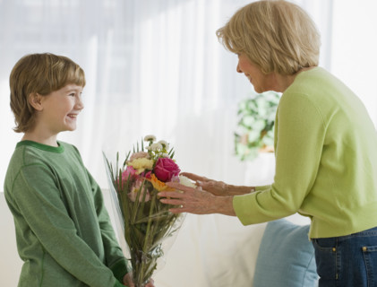 Grandson giving flowers to grandmother.
