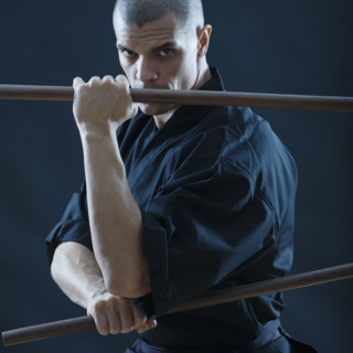 Hispanic male holding sticks in fighting stance.