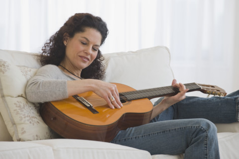 Hispanic woman playing guitar.