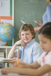 Boy holding pencil at school desk.