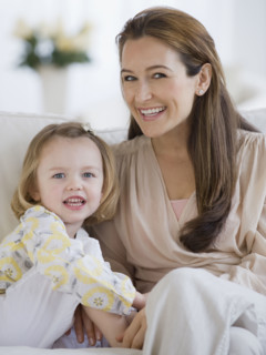 Mother and daughter sitting on sofa.