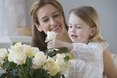 Mother watching daughter arrange flowers.