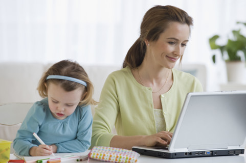 Mother working next to daughter coloring.