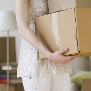 Woman carrying stack of moving boxes.