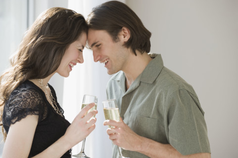 Couple holding champagne and touching foreheads.