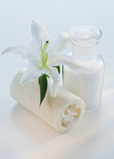 Flower and loofah next to bath salts.