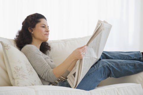 Hispanic woman reading newspaper.