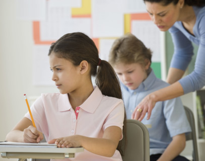 Hispanic girl writing at school desk.