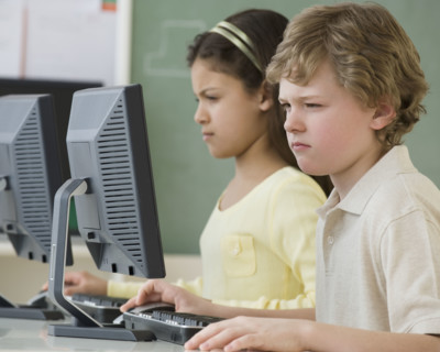 Multi-ethnic school children looking at computers.