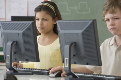 Multi-ethnic school children looking at computers.