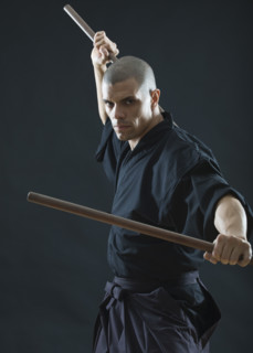 Hispanic male holding sticks in fighting stance.