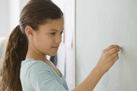 Hispanic girl writing on blackboard.