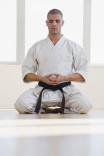 Hispanic male karate black belt meditating.