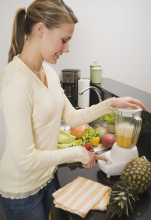 Woman pushing button on blender.