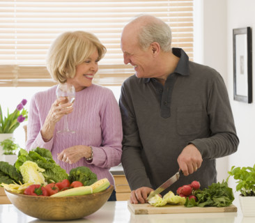 Senior couple chopping vegetables and drinking wine.