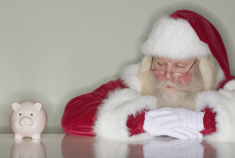 Santa Claus looking at piggy bank.