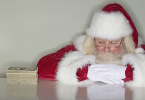 Santa Claus looking at stack of money.