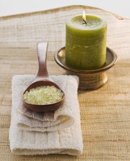 Bath salt in spoon next to candle.