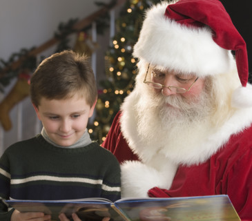 Santa Claus and boy reading book.