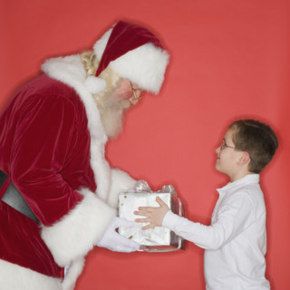 Santa Claus handing gift to boy.