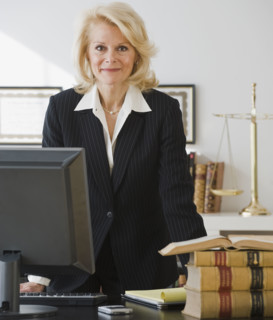 Businesswoman leaning on desk.