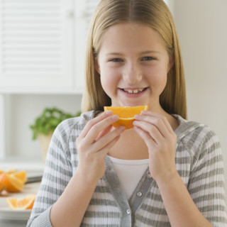 Girl eating orange slice.