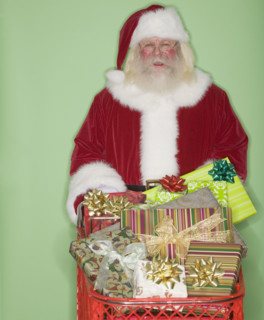Santa Claus pushing shopping cart of gifts.