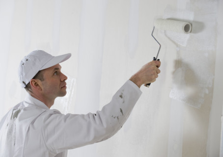Male painter painting with paint roller.