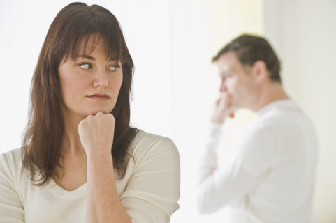 Upset woman with husband in background.