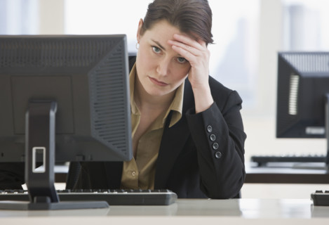 Frustrated businesswoman leaning on desk.
