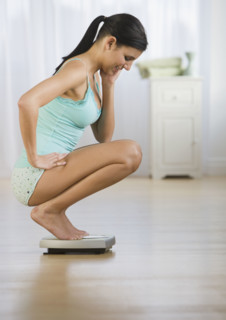 Woman crouching on scale.
