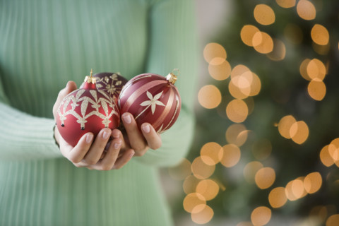Woman holding Christmas ornaments.